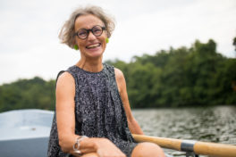 Ältere Frau mit schwarzer Brille lachend auf einem Ruderboot. - Augen