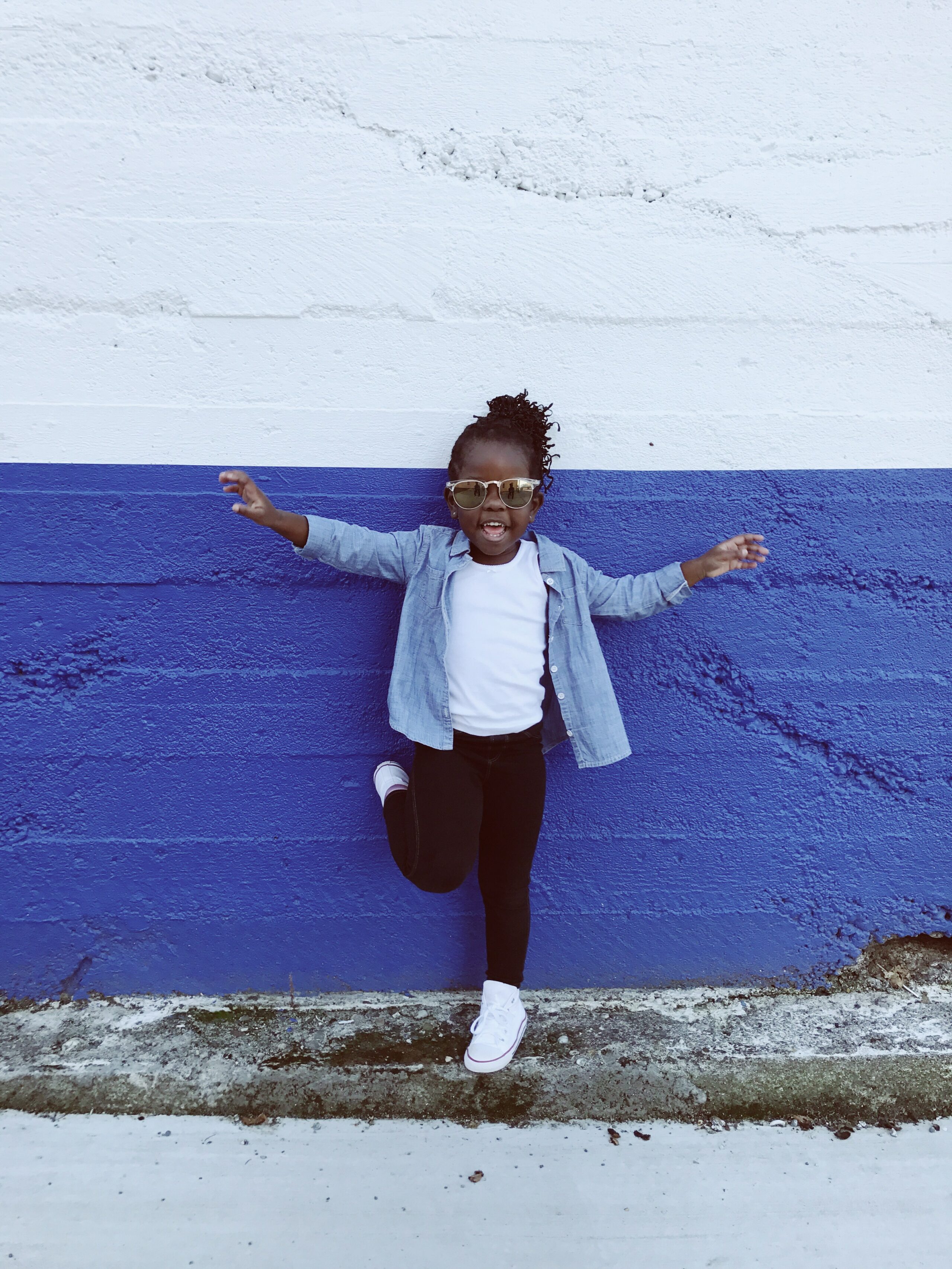 Ein dunkelhäutiges Kind steht vor einer blau-weissen Wand