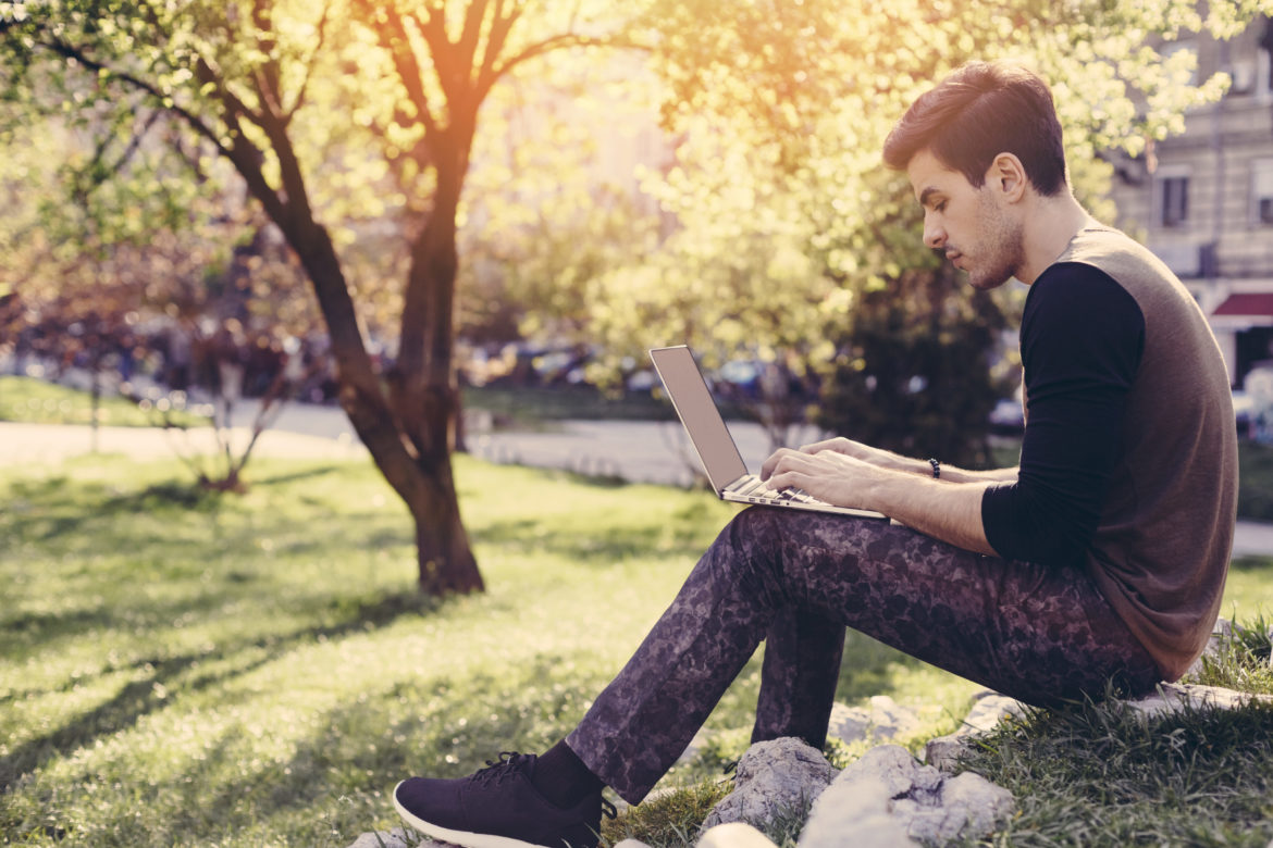 Ein junger Mann mit Laptop im Park