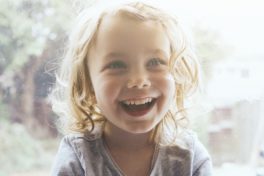 Lächelndes Kind mit Sonnenstrahlen im Gesicht