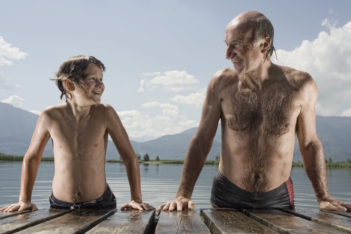 Erblich bedingten Haarausfall stoppen: Grossvater und Enkel stützen sich nebeneinander an einem Steg aus dem Wasser.