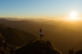 Frau macht Yoga auf einem berg bei Sonnenaufgang. _Psyche und Krebs