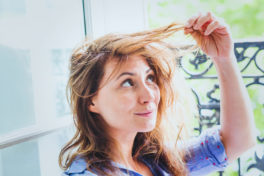 Erblich bedingter Haarausfall Frau: Frau hält Haare und sieht nachdenklich aus