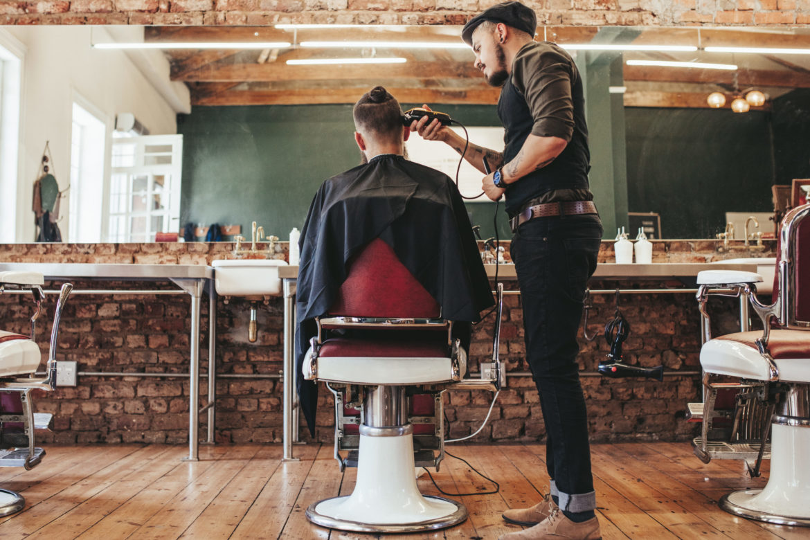 Ein Friseur schneidet einem Mann die Haare in einem Salon.