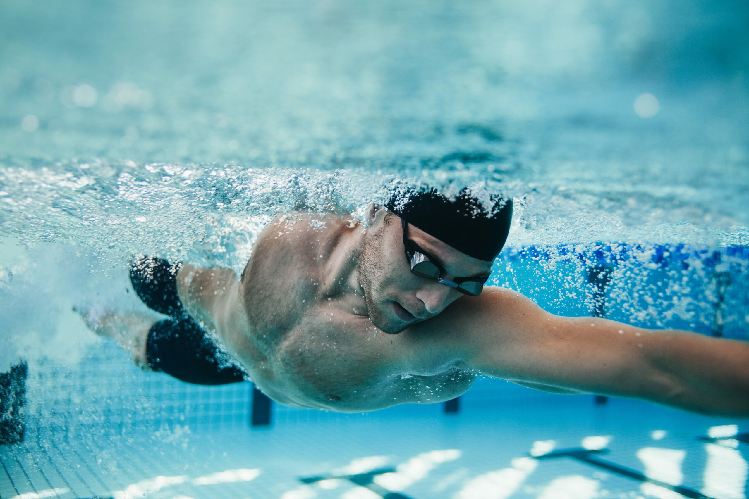 Schwimmer trainiert im Hallenbad und ist unter Wasser zu sehen.