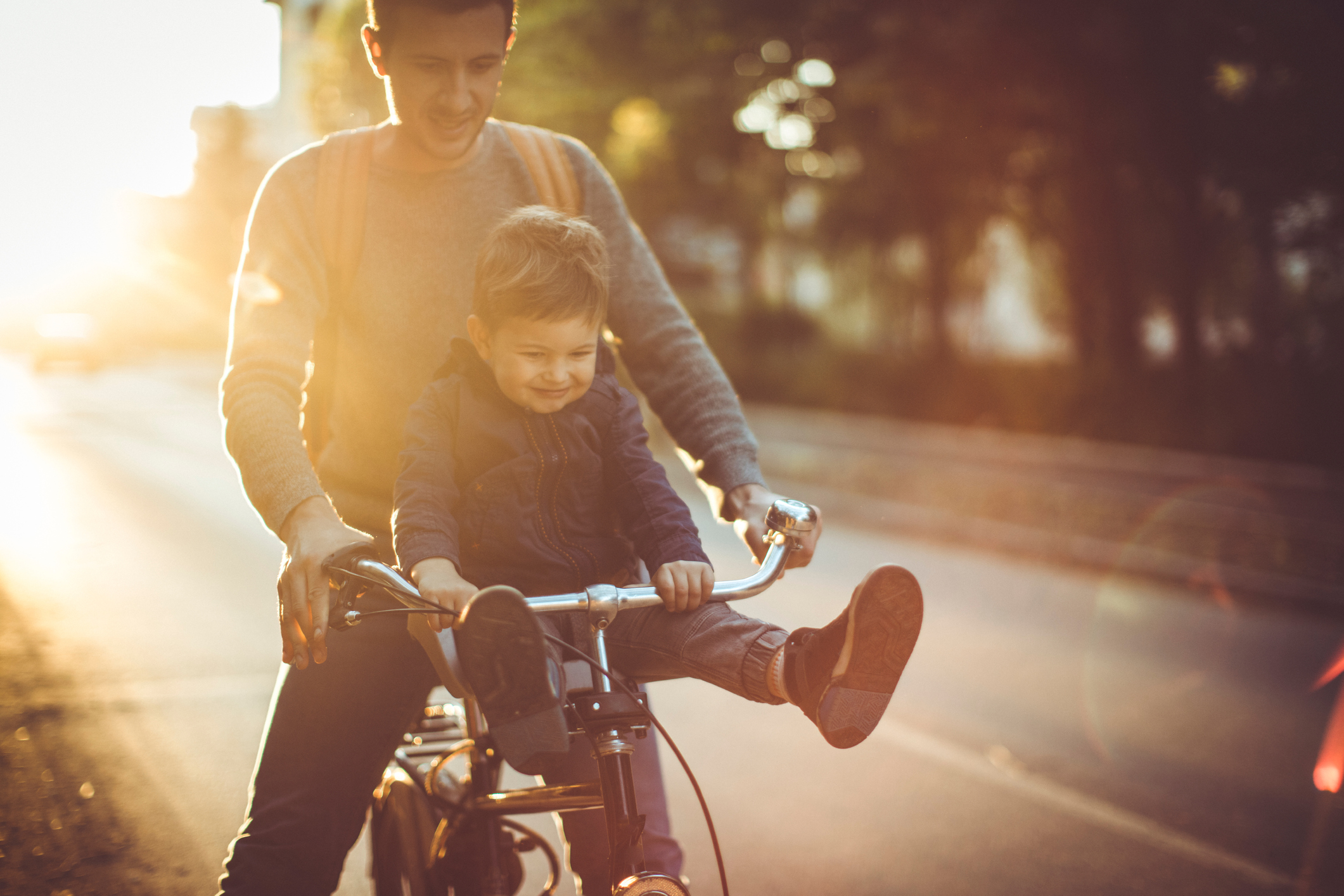Junger Mann fährt mit kleinem Jungen auf der Stange Fahrrad.