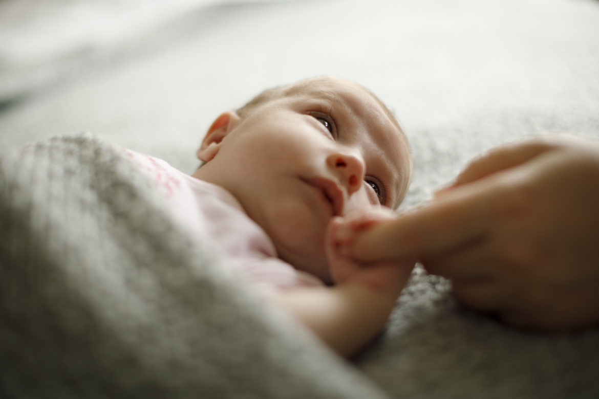 Neugeborenes hält Finger