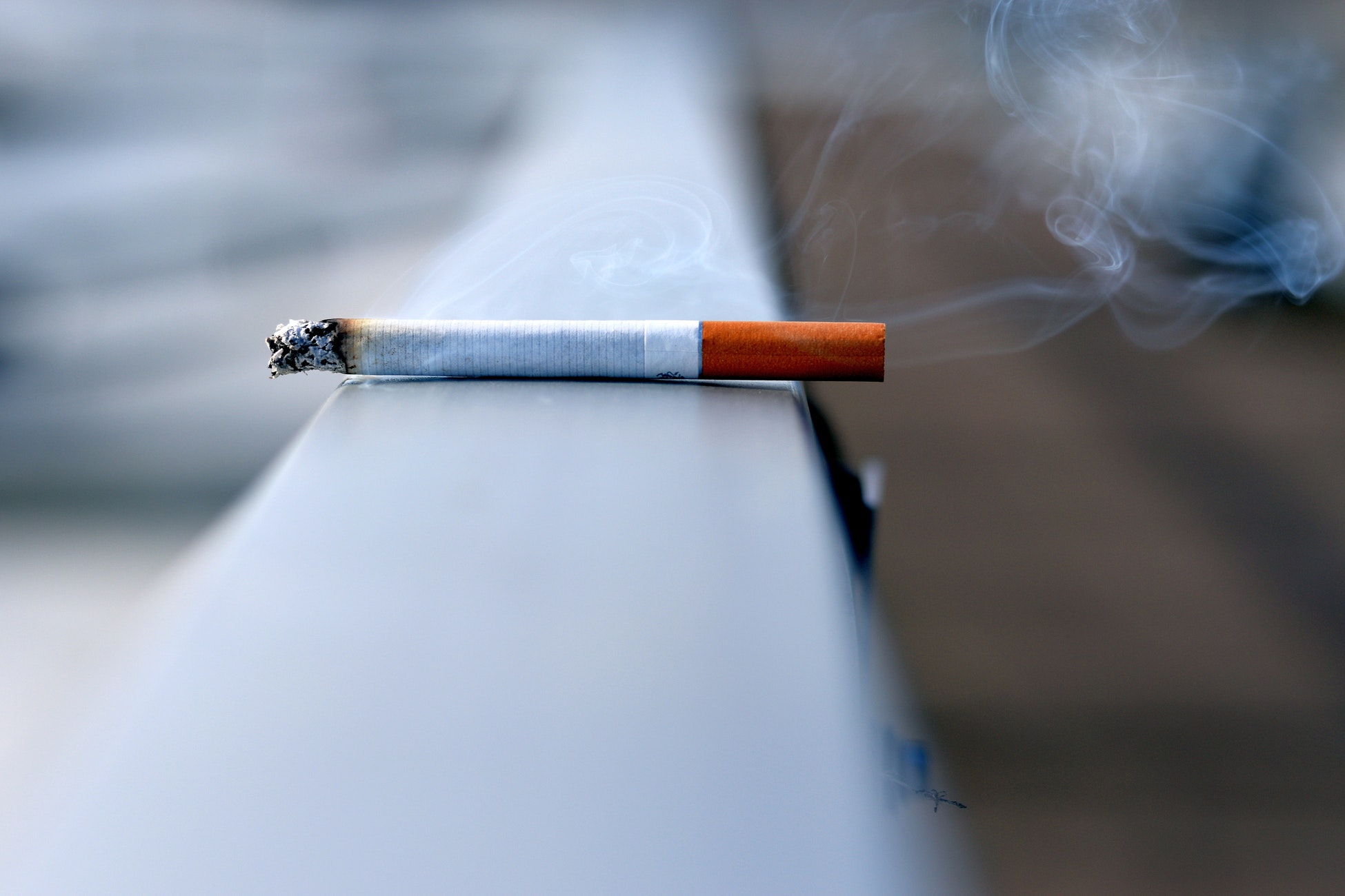 Ein brennende Zigarette auf einem Geländer.