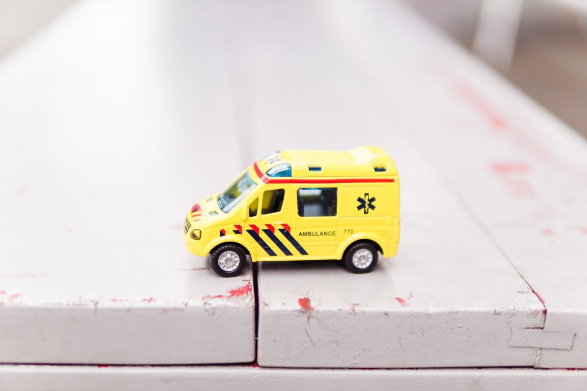 Ein kleiner Spielzeug Krankenwagen auf weissen Holzdielen.