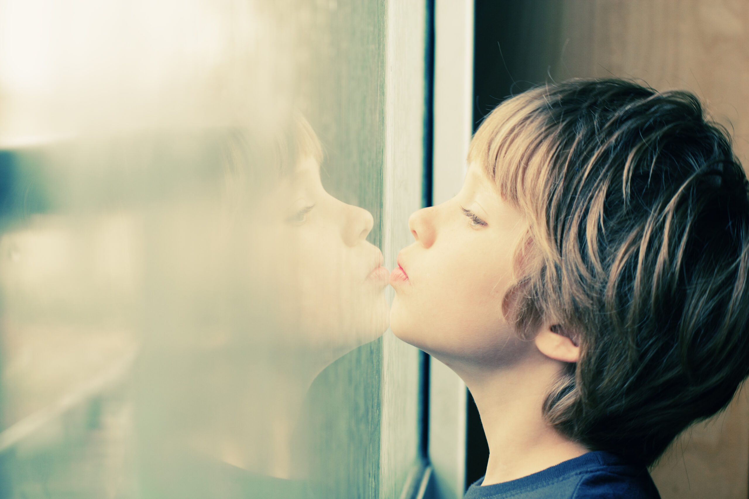 Junge guckt durch Fenster-Sehfehler Kinder