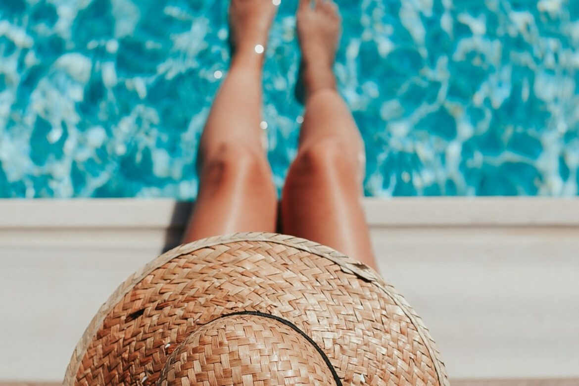 Hitzschlag vorbeugen: Person mit Hut und den Füssen im Pool
