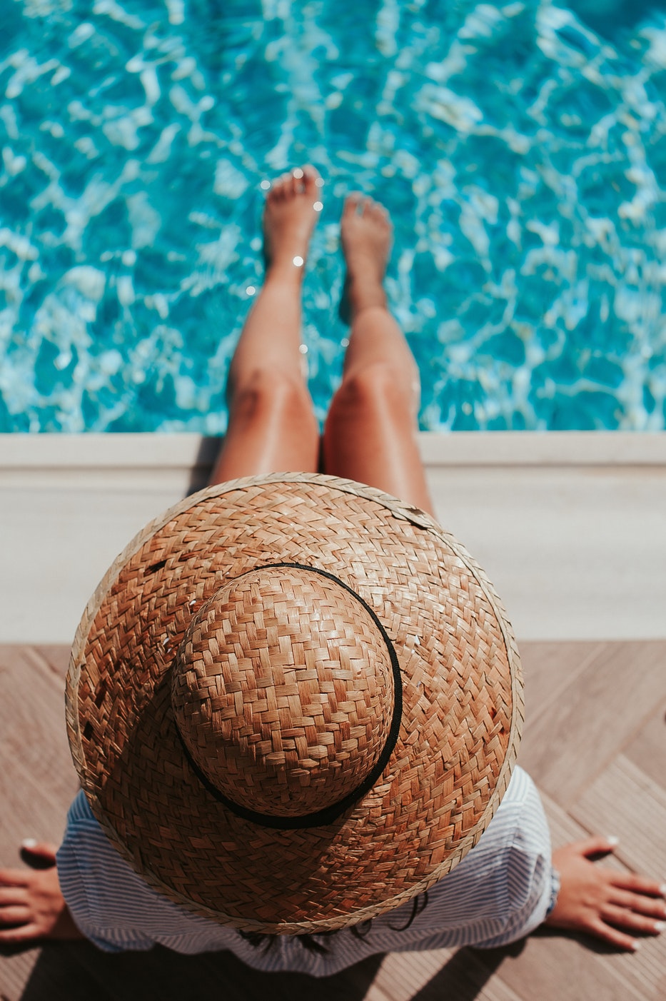 Hitzschlag vorbeugen: Person mit Hut und den Füssen im Pool
