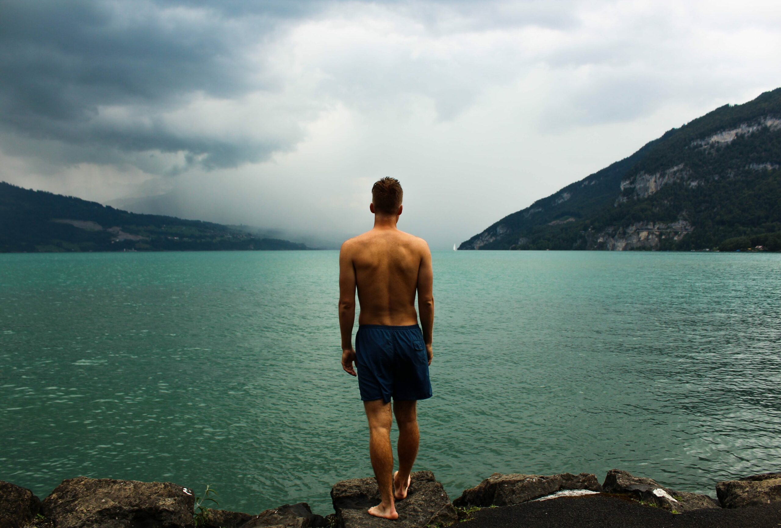 Mann in Badehose steht am See
