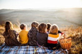 Freizeit gestalten: Kinder sitzen nebeneinander auf einer Wiese