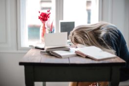 Burnout-Prophylaxe: Frau mit Kopf auf dem Schreibtisch