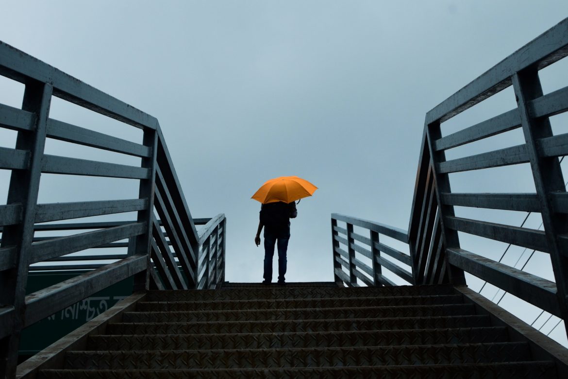 Person mit Regenschirm auf Treppe