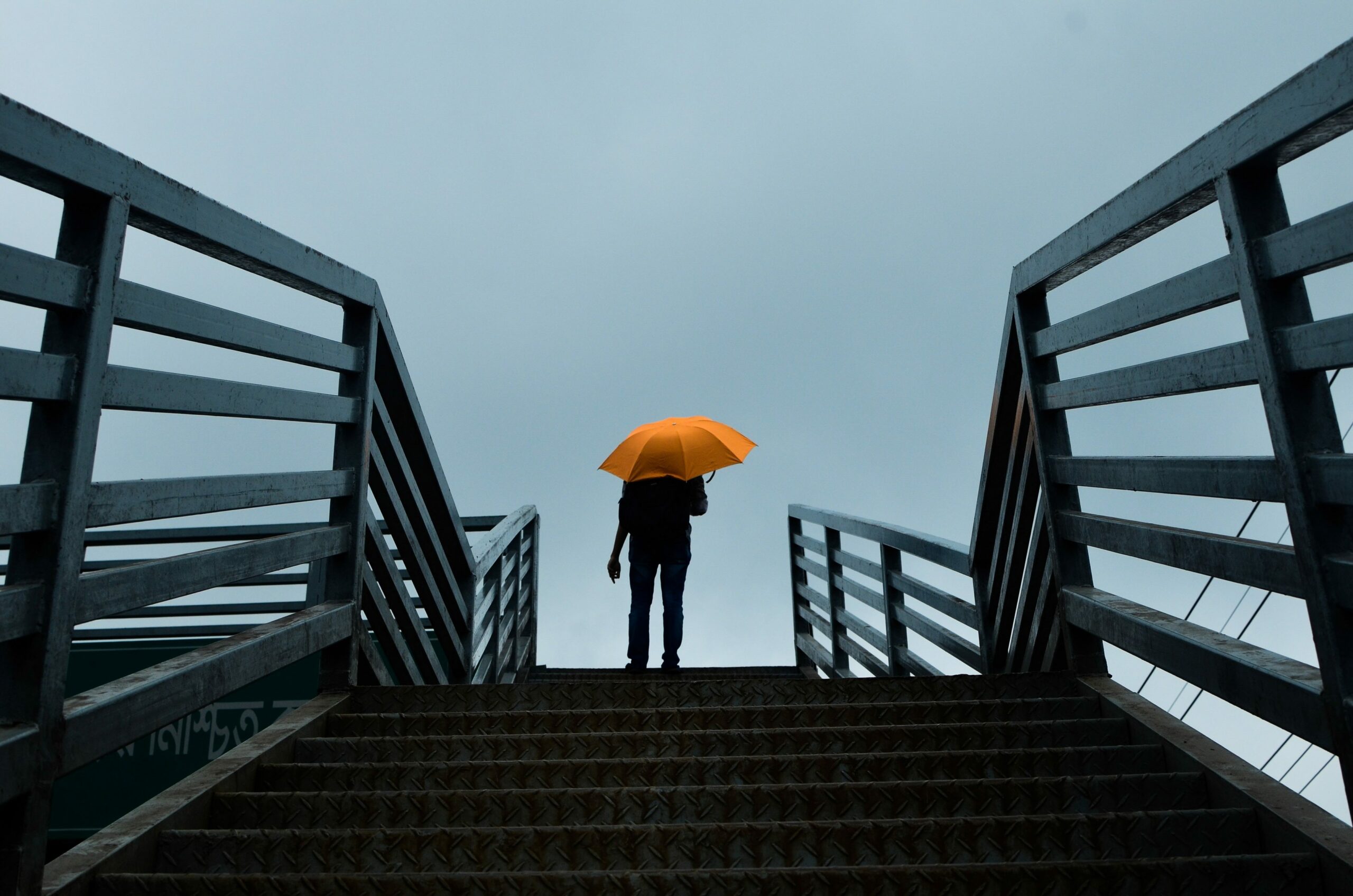 Person mit Regenschirm auf Treppe