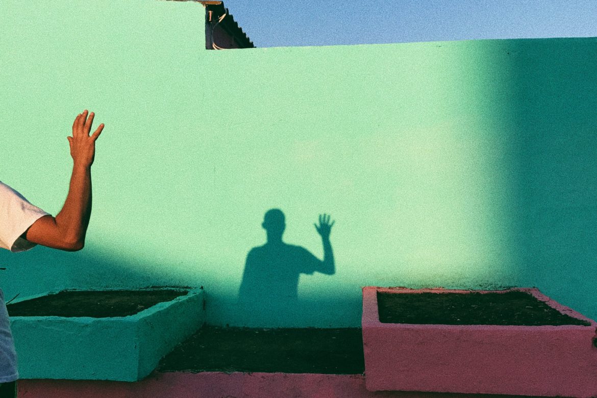 Stress loswerden: Schatten einer Person mit gehobenem Arm auf einer grünen Wand