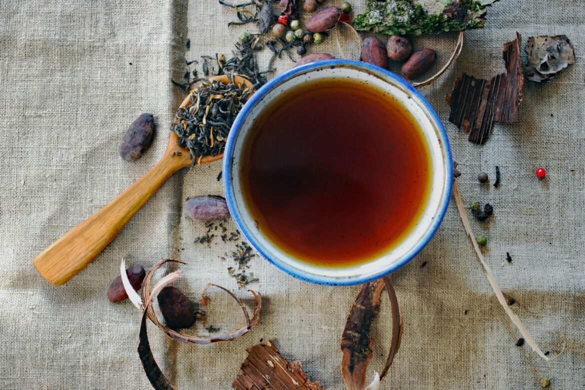 Tasse Tee und ein Holzlöffel mit getrockneten Lavendelblüten