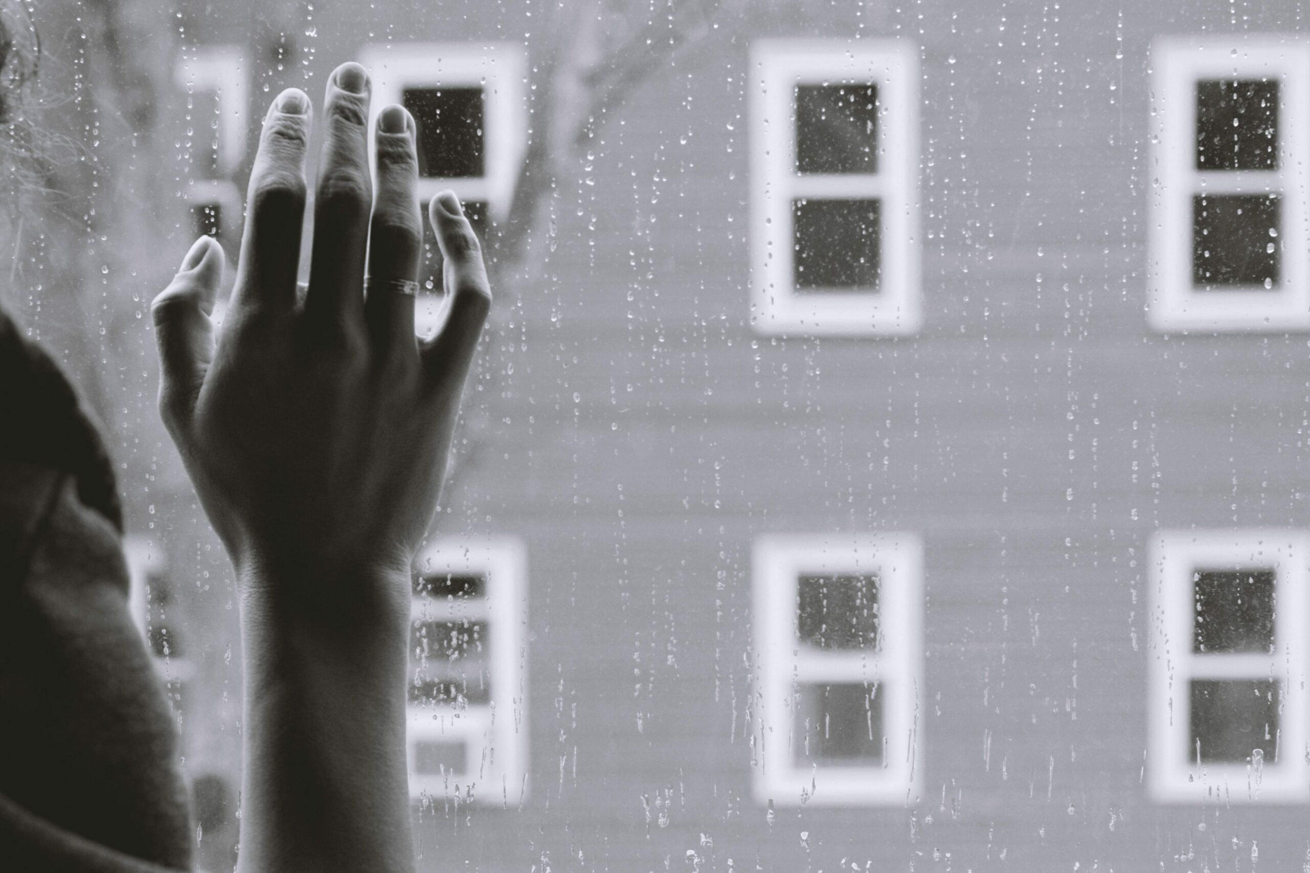 Soziale Angststörung: Frauenhand an verregnetem Fenster