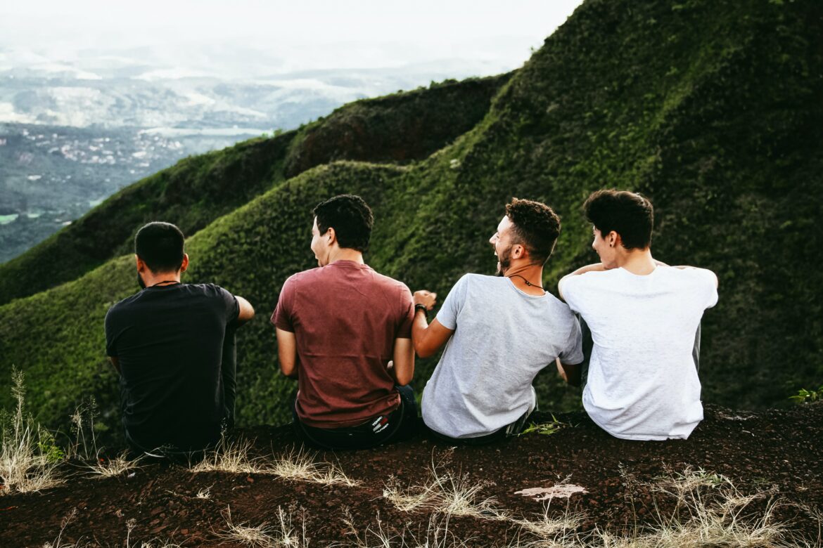 Eine Reihe Männer sitzt mit Blick auf bewaldete Berge