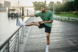 Arthrose Hüftgelenk: Mann in Sportkleidung, der sich an einem Geländer dehnt