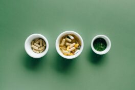 Darreichungsformen Medikamente: Drei Schalen mit unterschiedlichen Pillen und Dragees auf grünem Untergrund