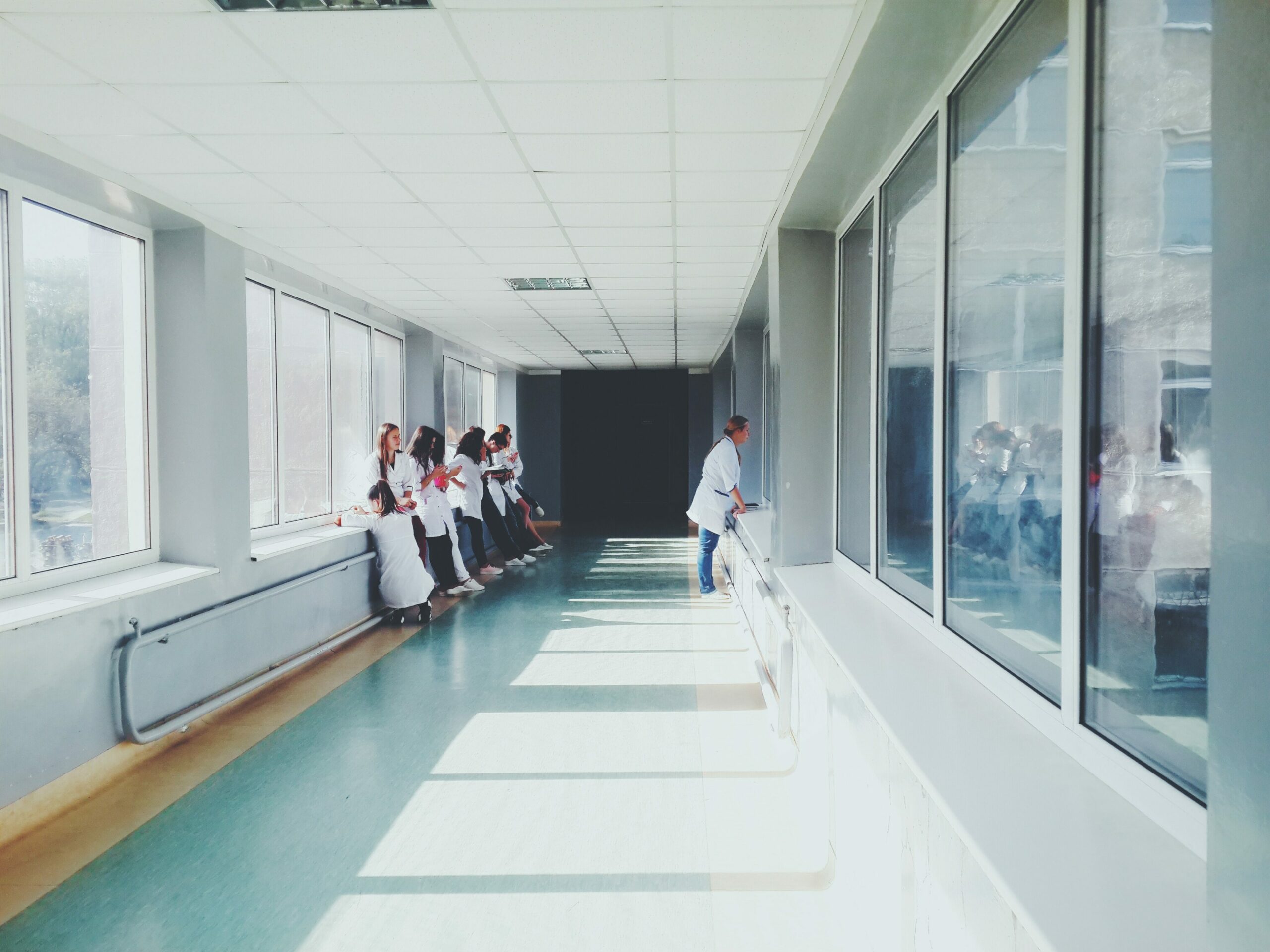 Versorgungsqualität Gesundheitswesen: Ein Krankenhausflur, in dem mehrere Mitarbeitende aufgereiht warten