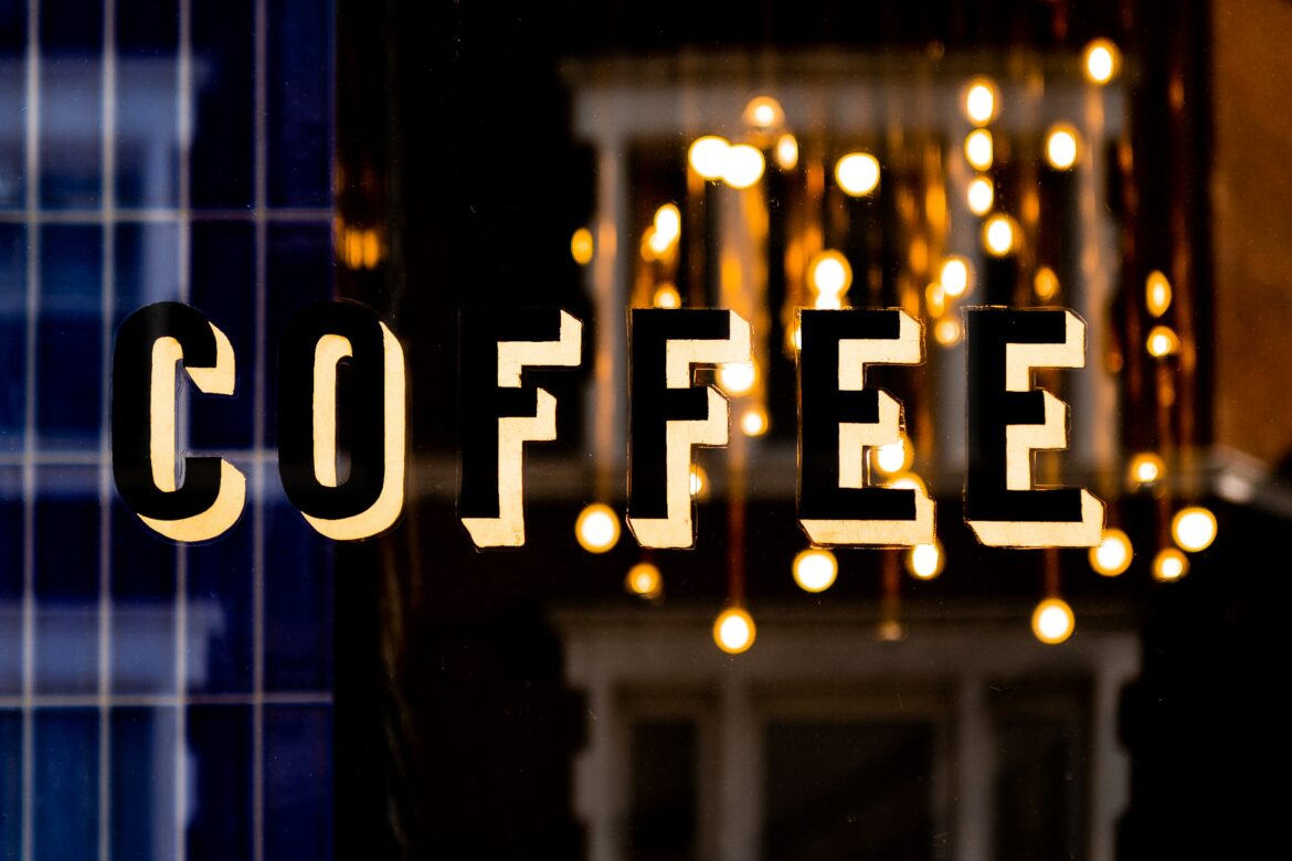Kaffee Herz: Englischer Schriftzug Coffee auf einer Scheibe, verschwommene Lichter im Hintergrund