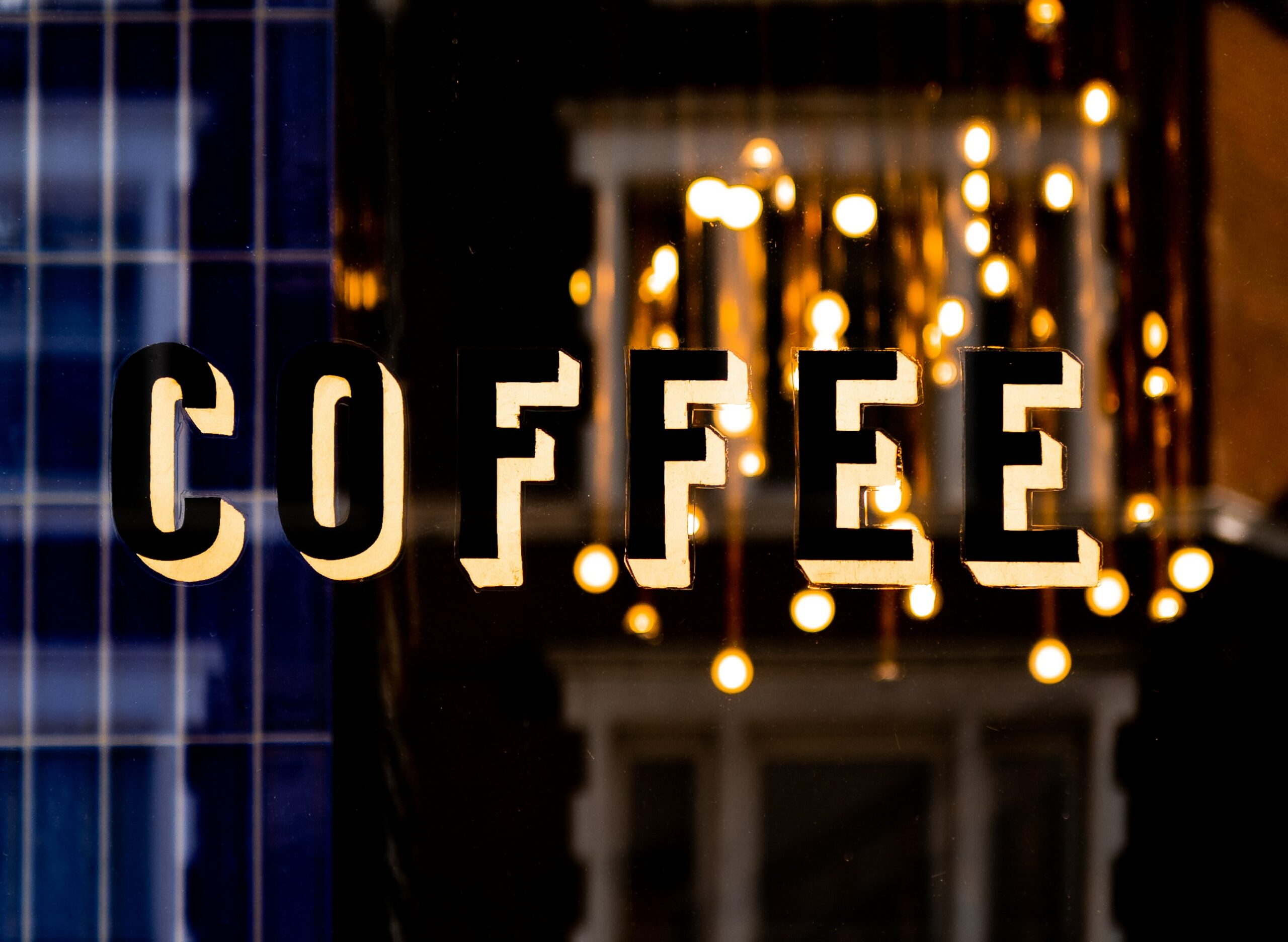 Kaffee Herz: Englischer Schriftzug Coffee auf einer Scheibe, verschwommene Lichter im Hintergrund