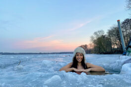 Winterschwimmen: Junge Frau zwischen badet in einem Eisloch eines zugefrorenen Sees.