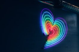 Transmenschen Schweiz: regenbogenfarbenes Herz aus Neonröhren vor einer dunklen Wand