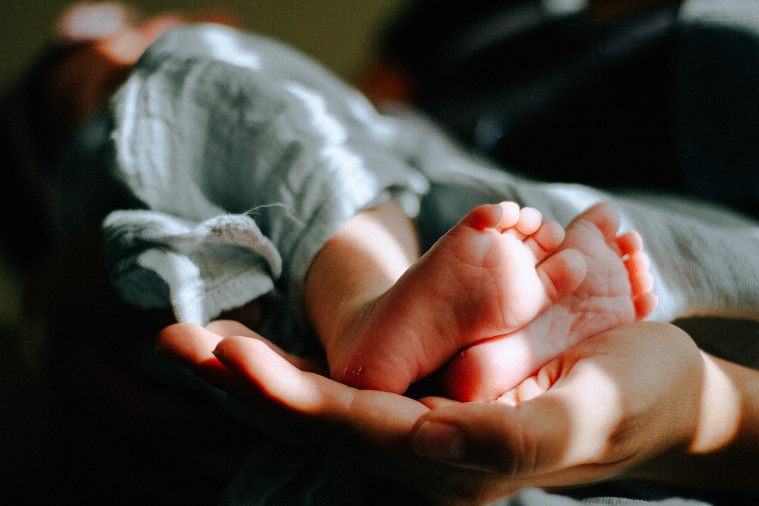 Fieber Säugling: Babyfüsse in erwachsener Hand