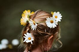 Kopfhautpflege: Mädchenkopf von hinten mit Blumen im Haar