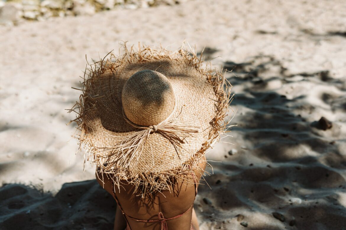 Hautkrebsprävention: Frau mit Strohhut am Strand