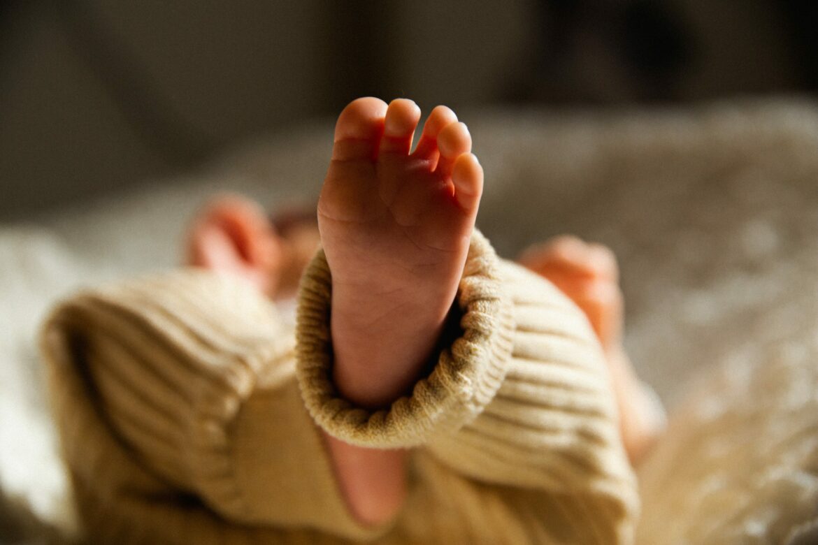 Kaiserschnitt Mikrobiom: Füsse eines Neugeborenen mit beiger Hose.