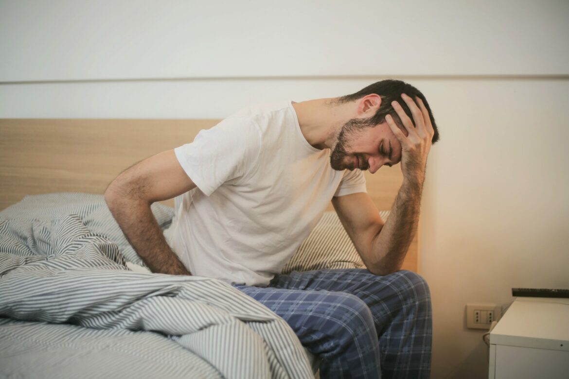 Morbus Crohn und Colitis Ulcerosa: Mann sitzt mit Schmerzen auf der Bettkante