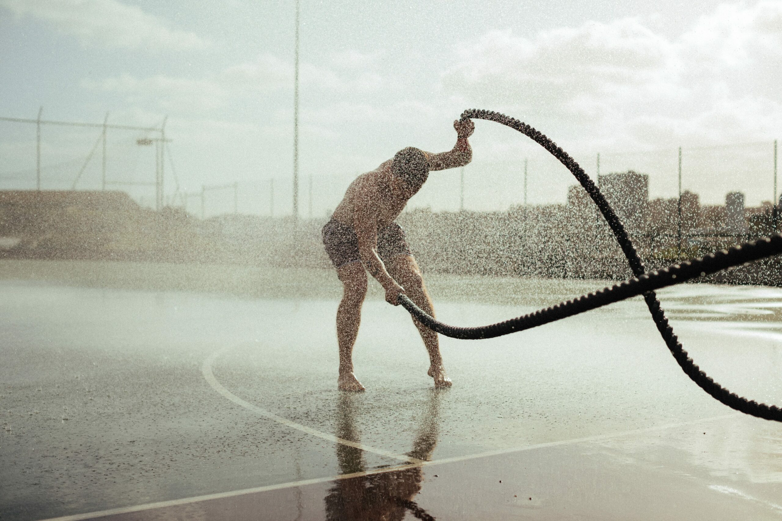 Krafttraining Muskelaufbau: Man beim Battle-Rope-Training im Regen