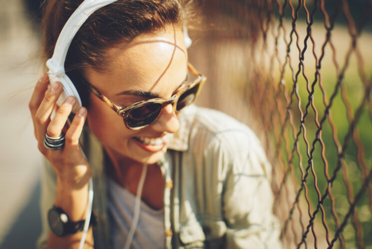 Musik und Gesundheit: junge Frau hört über Kopfhörer Musik und lächelt