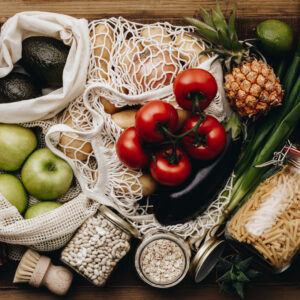 Nachhaltig ernähren: Auswahl an Gemüse und Früchten in einer Netztasche auf dem Tisch