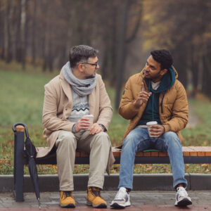 Christliche Seelsorge: Zwei Männer sitzen auf einer Bank und unterhalten sich.