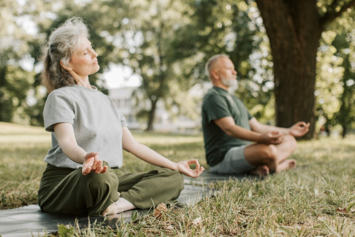 Senioren Hobbys: Ein älteres Paar macht im Park Yoga.
