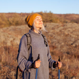 Gesunde Atemwege: junge Frau atmet beim Wandern in der Herbstsonne tief durch.