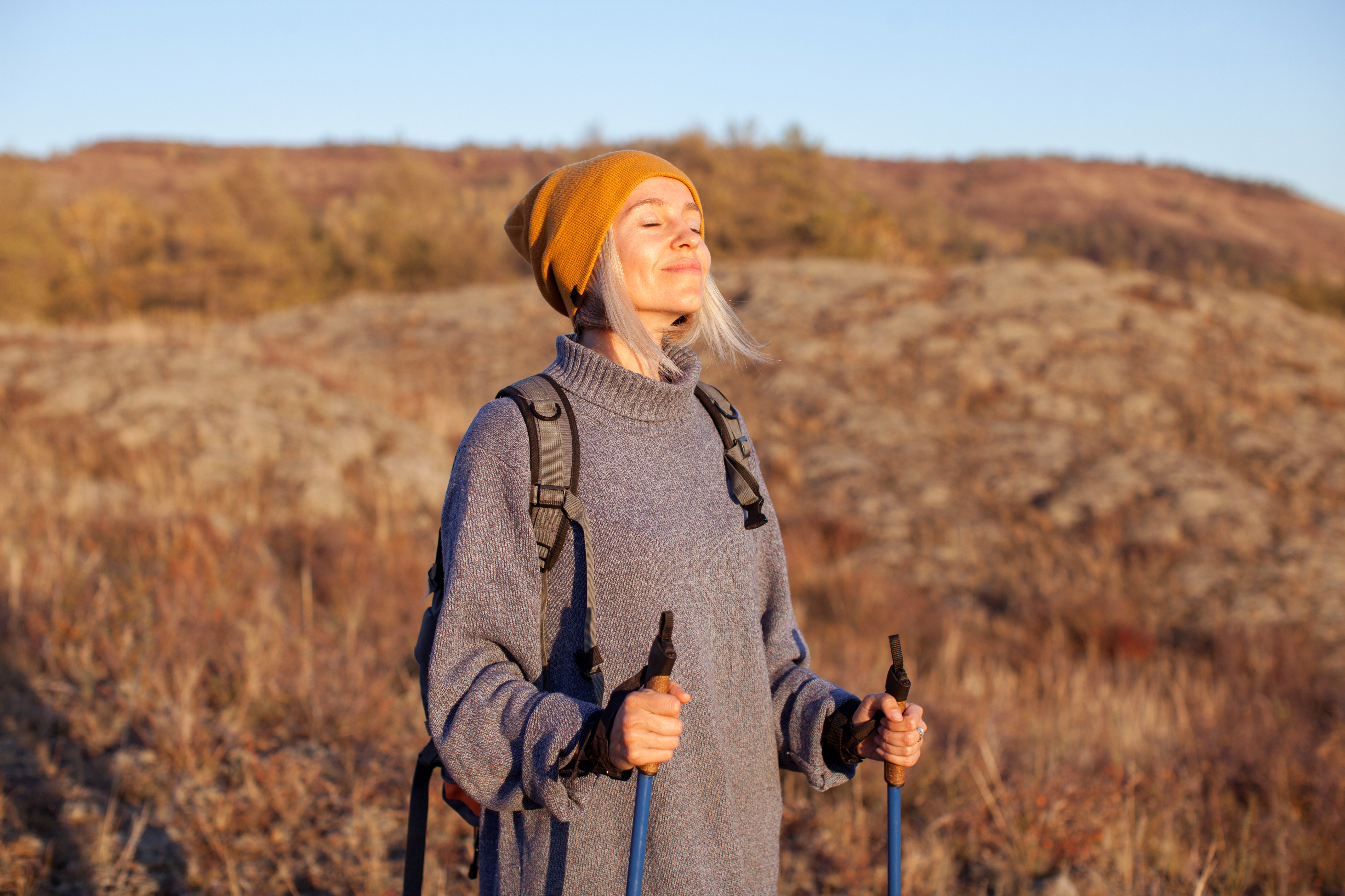 Gesunde Atemwege: junge Frau atmet beim Wandern in der Herbstsonne tief durch.