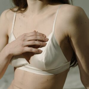 Brustuntersuchung Vorsorge: Frau fasst sich im Sitzen an die Brust.