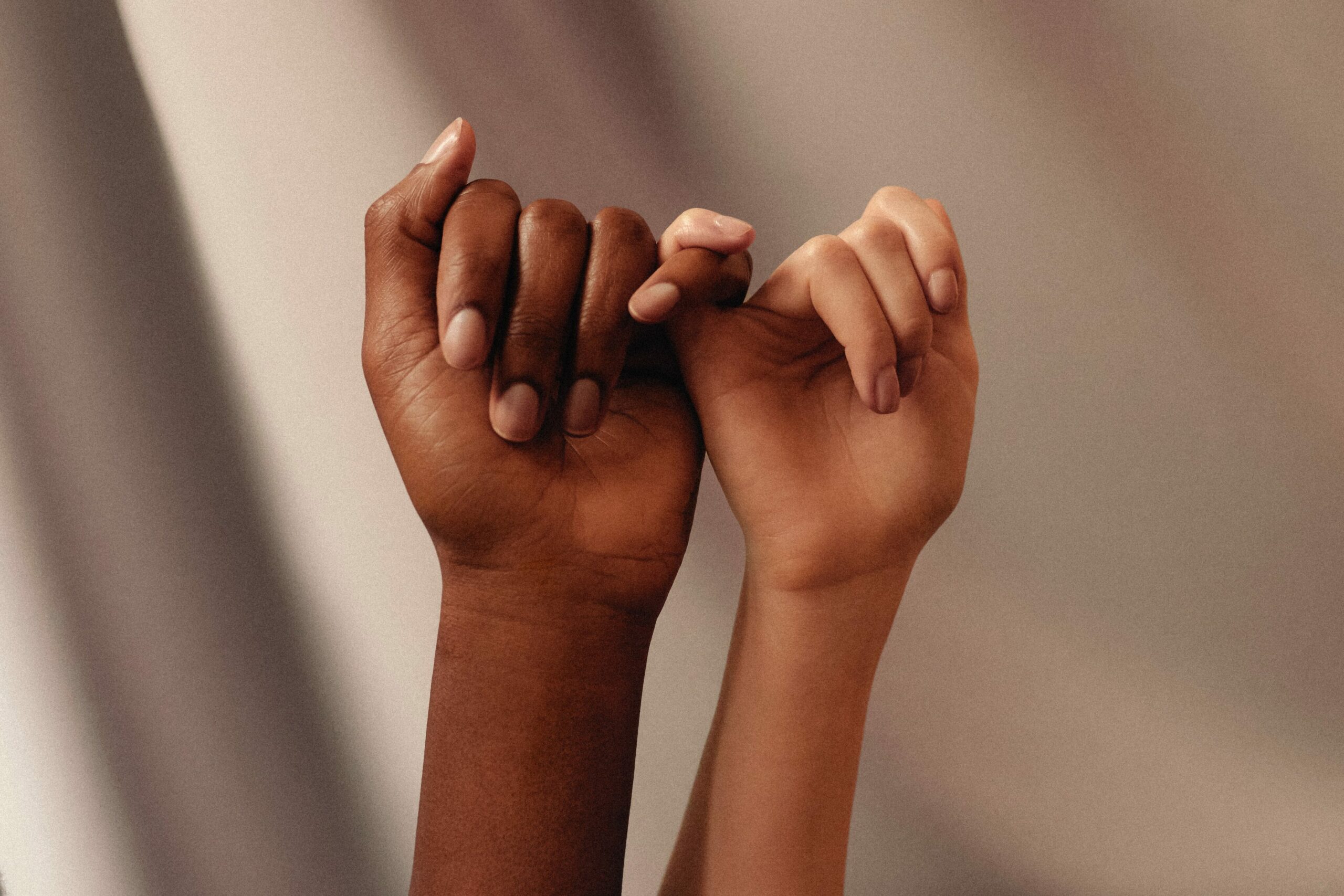 Krebsvorsorge bei Frauen: zwei Hände halten sich am kleinen Finger