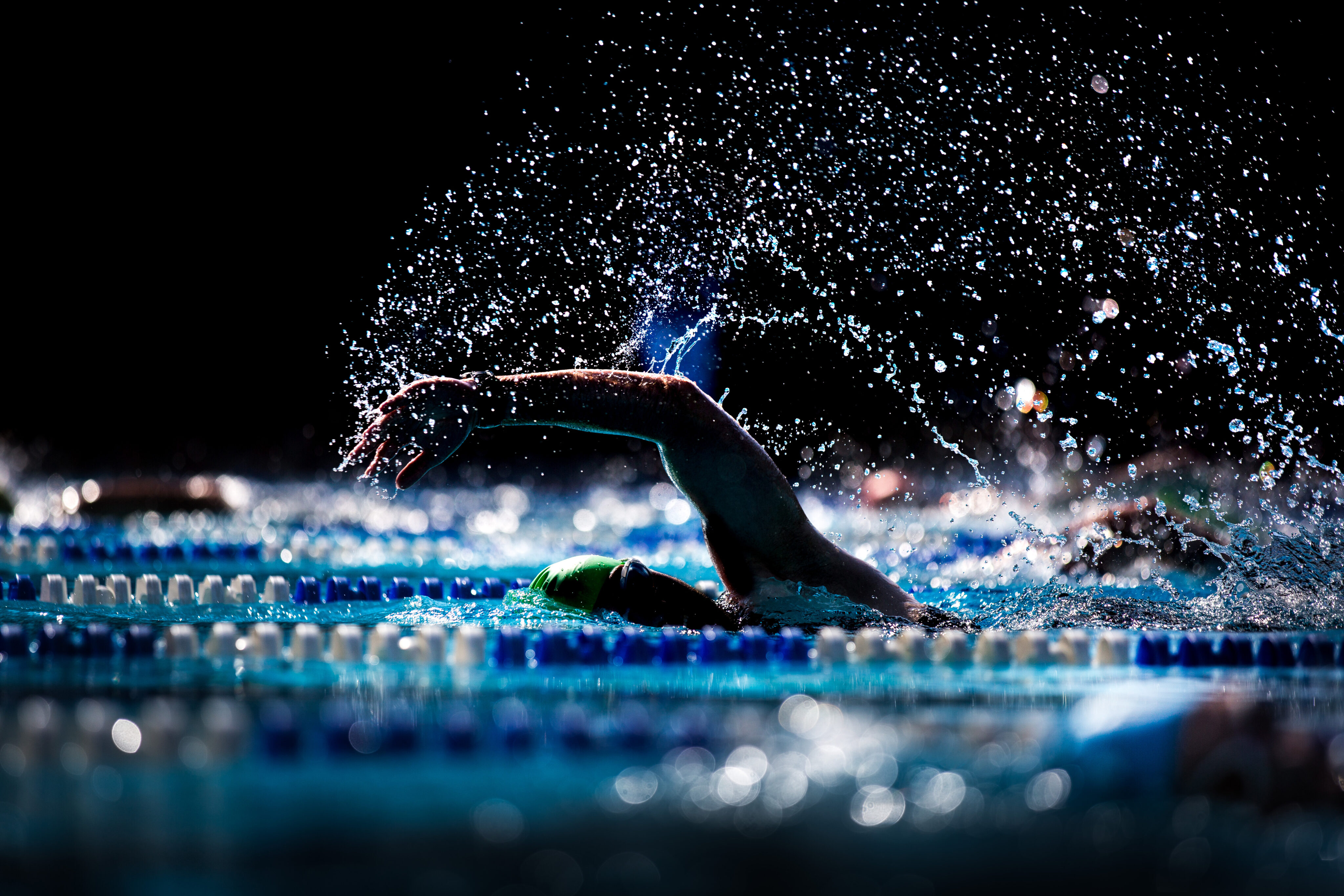 Bewegung Lebenserwartung: Der Arm eines Schwimmers im Freistil ragt aus dem Wasser.