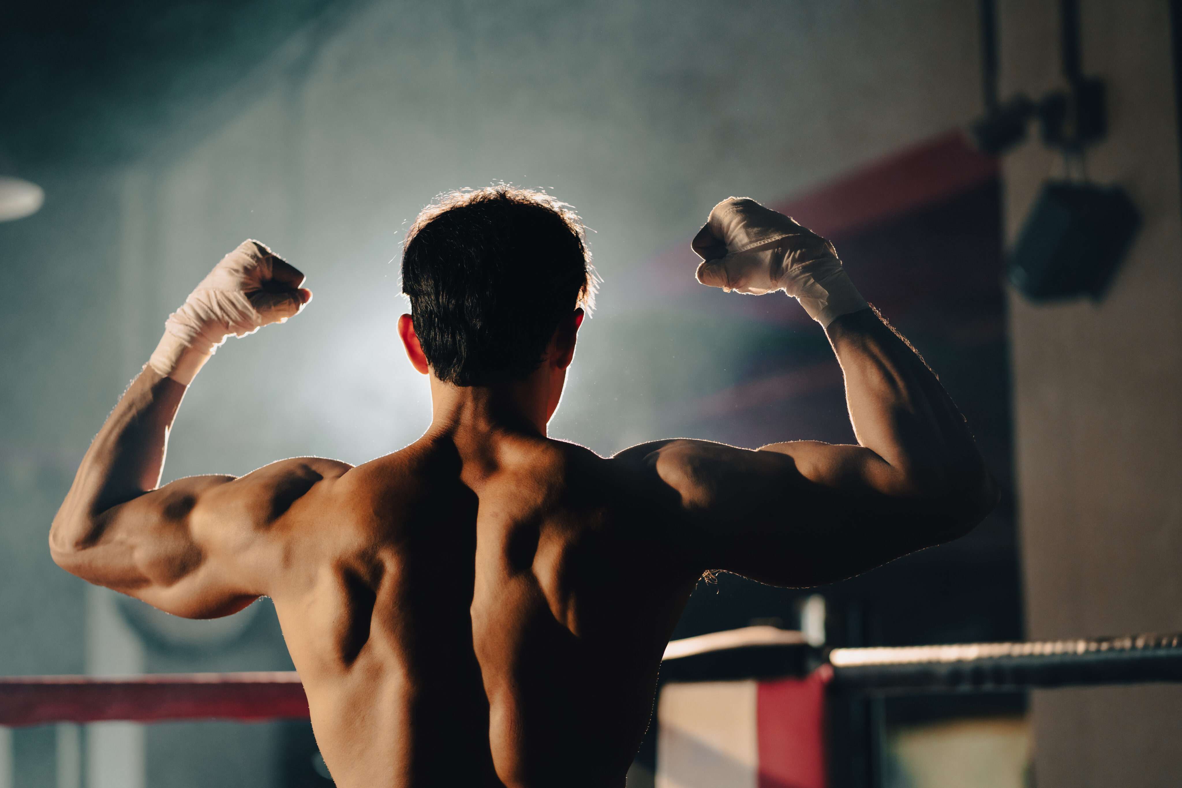 Toxische Maskulinität: Mann reckt nach einem Boxkampf Hände in die Luft.