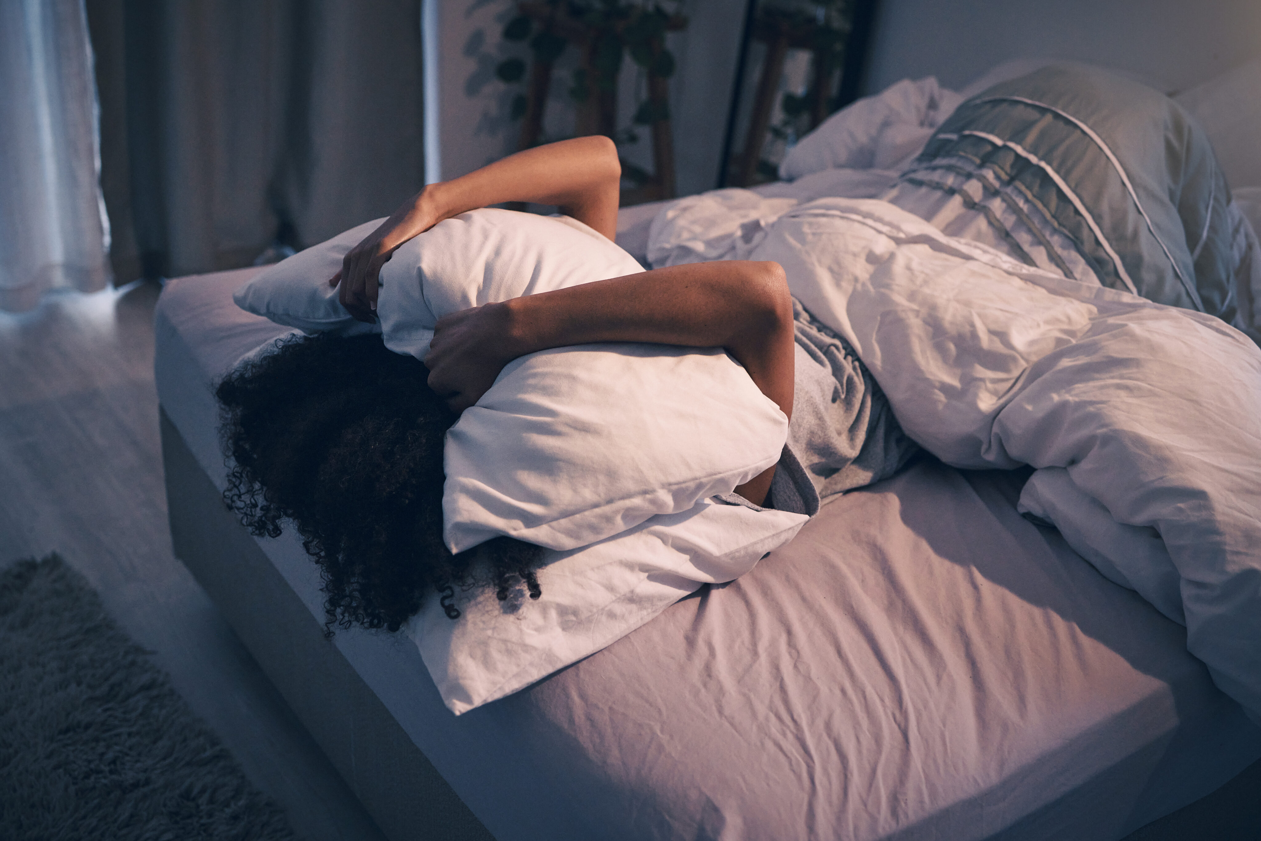 Schlaf messen: Frau liegt im Bett und bedeckt ihr Gesicht mit einem Kissen