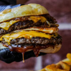Hochverarbeitete Lebensmittel Gesundheit: Burger mit viel verarbeitetem Fleisch und Sauce in Nahaufnahme